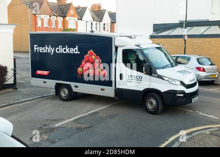 Tesco supermarket / super market delivery van in a residential street or road making home delivery & blocking the junction & flow of traffic. UK (122) Stock Photo