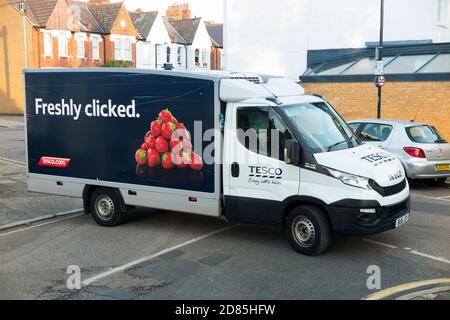 Tesco supermarket / super market delivery van in a residential street or road making home delivery & blocking the junction & flow of traffic. UK (122) Stock Photo