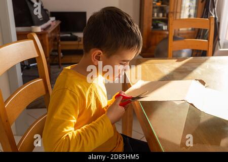 a preschool boy cuts out of cardboard or makes crafts on the New Year's theme, classes for children at home Stock Photo