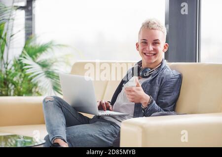 Young hipster guy in nice clothes sitting on sofa with laptop Stock Photo