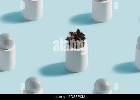 Abstract geometrical pattern from solid three-dimensional gypsum figures cylinders with balls and one pine cone in the center on a pastel blue backgro Stock Photo