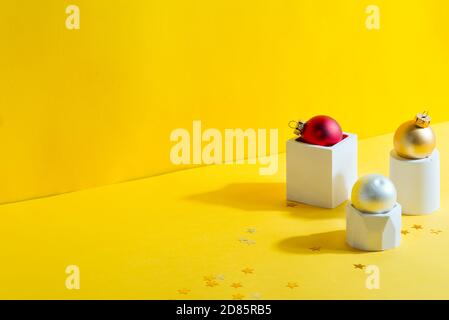 Festive Christmas composition from geometrical gypsum pots and figures with colored bright balls holiday decoration on a yellow background, copy space Stock Photo