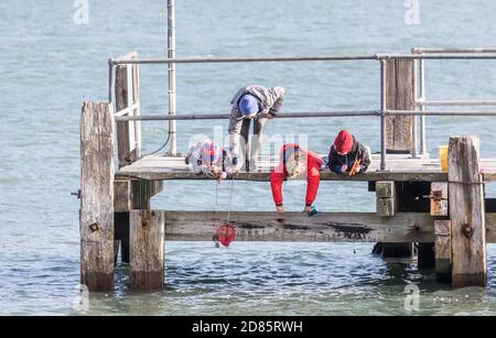 Currabinny, Cork, Ireland. 27th October, 2020. Jane O'Leary from Carrigaline helps her three children, Maymie, Billy and Paddy fish for crab on a cool afternoon on the pier at Currabinny, Co. Cork, Ireland.  - Credit; David Creedon / Alamy Live News Stock Photo