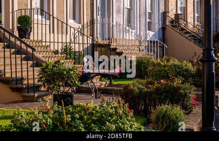 Woman relaxing in sun lounger in front garden outside house, Whitby, England, UK Stock Photo