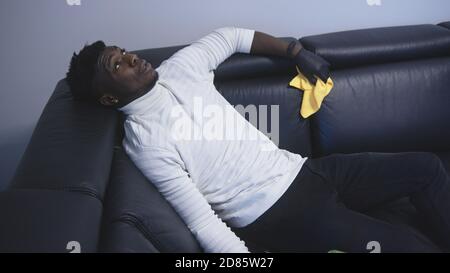 Exhausted african american black man resting on the couch after cleaning appartment. High quality photo Stock Photo