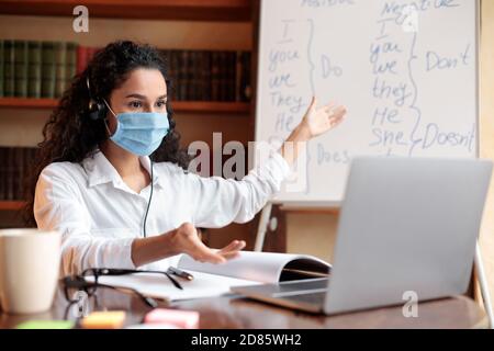 Teacher in mask having video conference chat with students Stock Photo