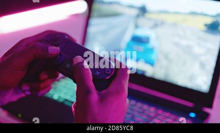 Warsaw, Poland 19.10.2020 close up, black man hand playing game on his laptop using video game console controlling joystick. High quality photo Stock Photo