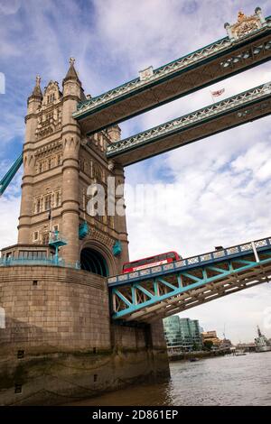 UK, London, Tower Bridge, view up from boat passing below tilting deck with London bus crossing Stock Photo