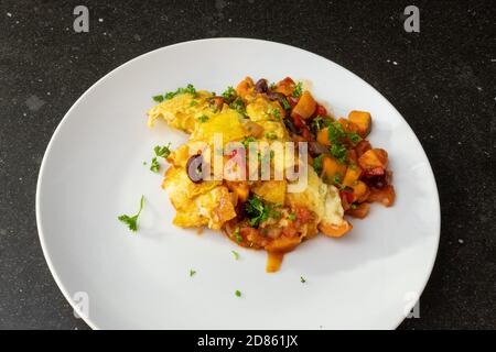 Lasagna served on a white plate at a dark kitchen table top Stock Photo