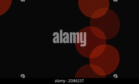 deep blurred dull Christmas lights light up slowly and fade out on dark backdrop Stock Photo