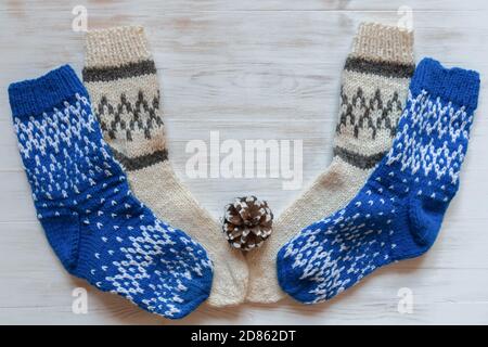 Blue and beige wool socks for winter and pine cone on white wood surface. Warm woolen socks for cold season and pine cones on brown vintage wood backg Stock Photo