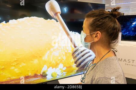 Woman wearing face mask looking at Samsung High definition QLED 8K Q850T television, TV screen in store.