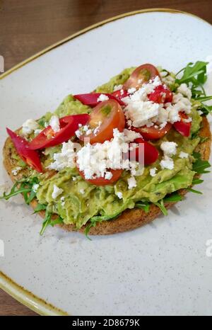 Smashed avocado on toast with red chillis, tomatoes and feta cheese - portrait Stock Photo