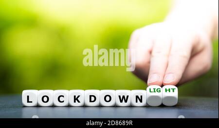 Symbol for a second lockdown. Hand turns dice and changes the expression "lockdown" to "lockdown light". Stock Photo