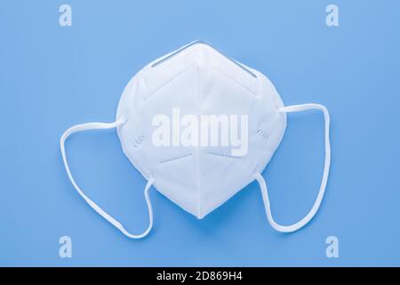 KN95 respirator, protective medical face filter mask. White isolated surgical cover. Protection concept from сoronavirus disease pandemic. Blue backgr Stock Photo