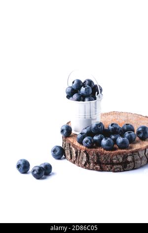 Freshly picked juicy blueberries on a wooden board in a white bucket. Blueberry antioxidant. Healthy eating concept. White background. Stock Photo
