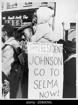 An African-American man holds a child on his shoulders as he carries a sign telling President Lyndon Johnson to 'Go To Selma Now,' New York, NY, 3/1965. (Photo by Stanley Wolfson/New York World-Telegram and the Sun Newspaper Photograph Collection/RBM Vintage Images) Stock Photo