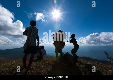 A group of porters carrying heavy load on Himalaya mountains in climbing season. Silhouette. Selective focus on porters. Stock Photo