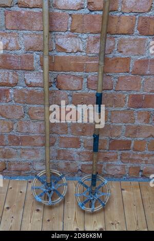 Close up macro view of very old vintage ski poles isolated on brick wall background. Stock Photo