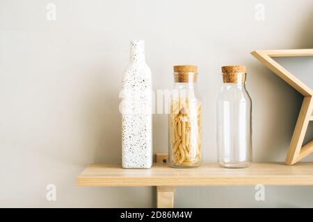 Wheat Italian pasta in glass jar on a wooden shelf in the kitchen. Stock Photo