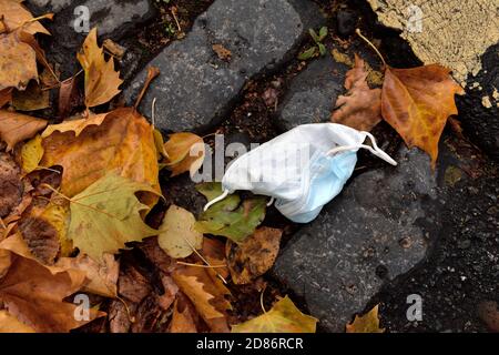 Hardly used disposable face mask for covid protection thrown away on street as litter, UK Stock Photo