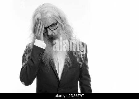 Studio shot of stressed senior bearded businessman having headache and wearing eyeglasses Stock Photo