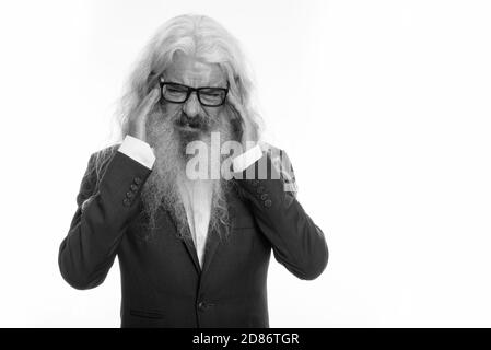 Studio shot of stressed senior bearded businessman wearing eyeglasses while having headache with both hands on head Stock Photo