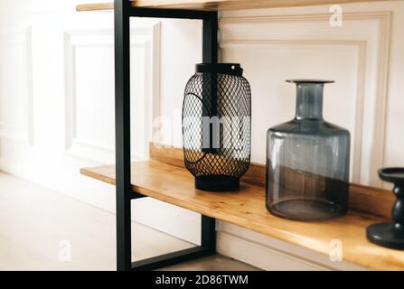 Stylish rack shelving with wooden shelves and decorative elements in living room Stock Photo