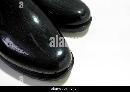 A part of black rubber boots with water drops on white background, copy space. Stock Photo
