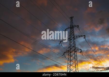 Transmission power tower on background of dramatic colorful sky. Lattice tower, used to support an overhead power line. Stock Photo