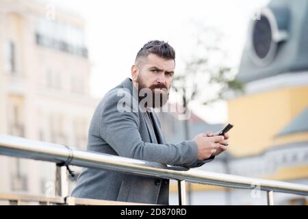 Staying up-to-date with new technology. Bearded man hold mobile phone urban outdoors. Modern communication. 3G. 4G. Modern lifestyle. Social media and SMS. Stock Photo