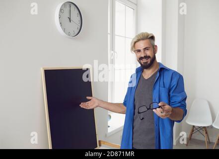 Smiling male worker explaining information from chalkboard Stock Photo