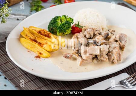 grilled chicken with rice and fried potatoes on white plate Stock Photo