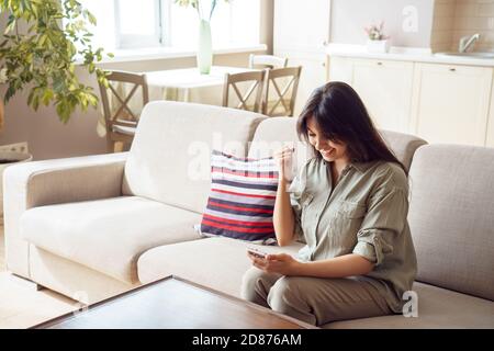 Happy young indian woman holding phone reading message celebrating success. Stock Photo