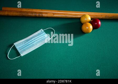 Blue medical face mask for Coronavirus on a green billiard table, protective medical mask for Covid-19 on pool,snooker table Stock Photo
