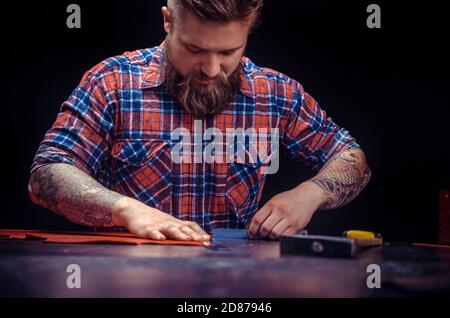 Leather Skinner creating new leatherwork at his workshelf Stock Photo