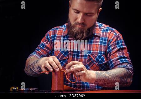 Craftsman produces leather workpiece at the workplace Stock Photo