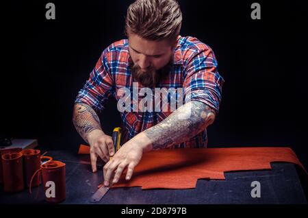 Leather man demostrating leather cutting process in the place of work Stock Photo