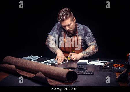 Artist working with leather produces leather workpiece at the workplace Stock Photo