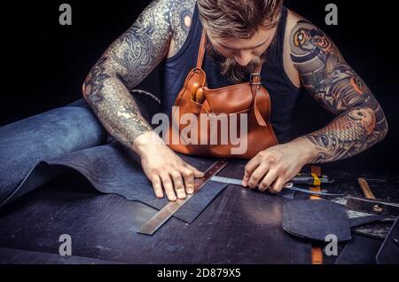 Leather Craftsman cuts out leather goods in workplace Stock Photo