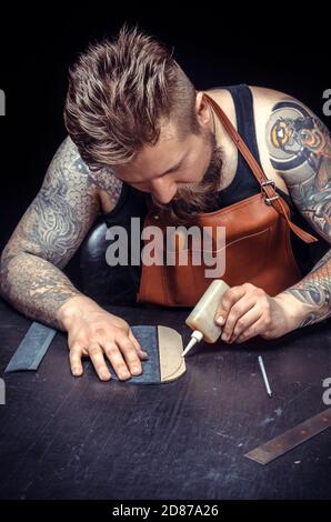 Leather Currier working on a new leather product at a workshop Stock Photo