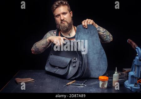 Leather Currier performs leather working for a new product in leather studio Stock Photo