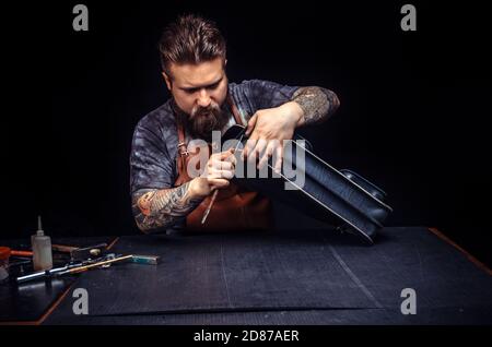 Craftsman working with leather processes a workpiece from leather Stock Photo