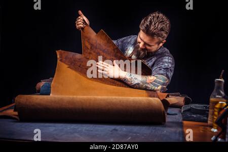 Handicraftsman produces leather goods at his desk Stock Photo