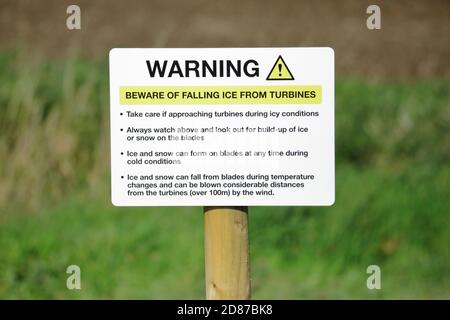 an  Ice warning sign by the side of wind turbines Stock Photo
