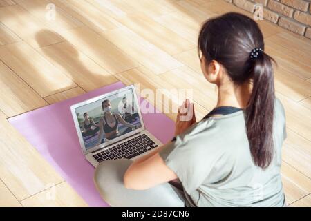 Young woman meditating watching online yoga class video tutorial at home. Stock Photo