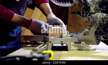 Joiner cuts off piece of wood blank using circular saw with laser in workshop Stock Photo