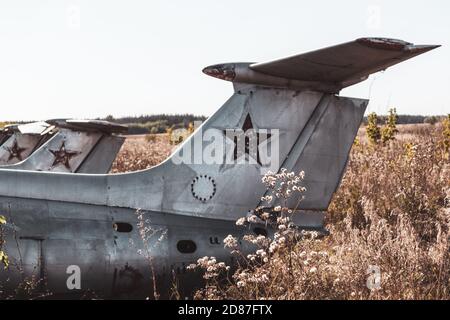 Old soviet plane fuselage and tail empennage close view in field. Aero L-29 Delfín a jet-powered trainer aircraft at abandoned Airbase remains in Vovc Stock Photo