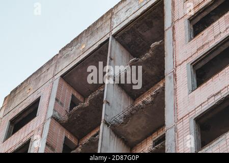 High multistorey abandoned soviet building facade with crashed balconies. Weathered housing estate, unfinished city of nuclear scientists in Birky, Uk Stock Photo