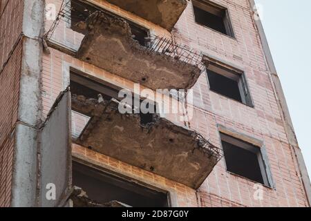 High multistorey abandoned soviet building facade with crashed balconies and red tiles. Weathered housing estate, unfinished city of nuclear scientist Stock Photo